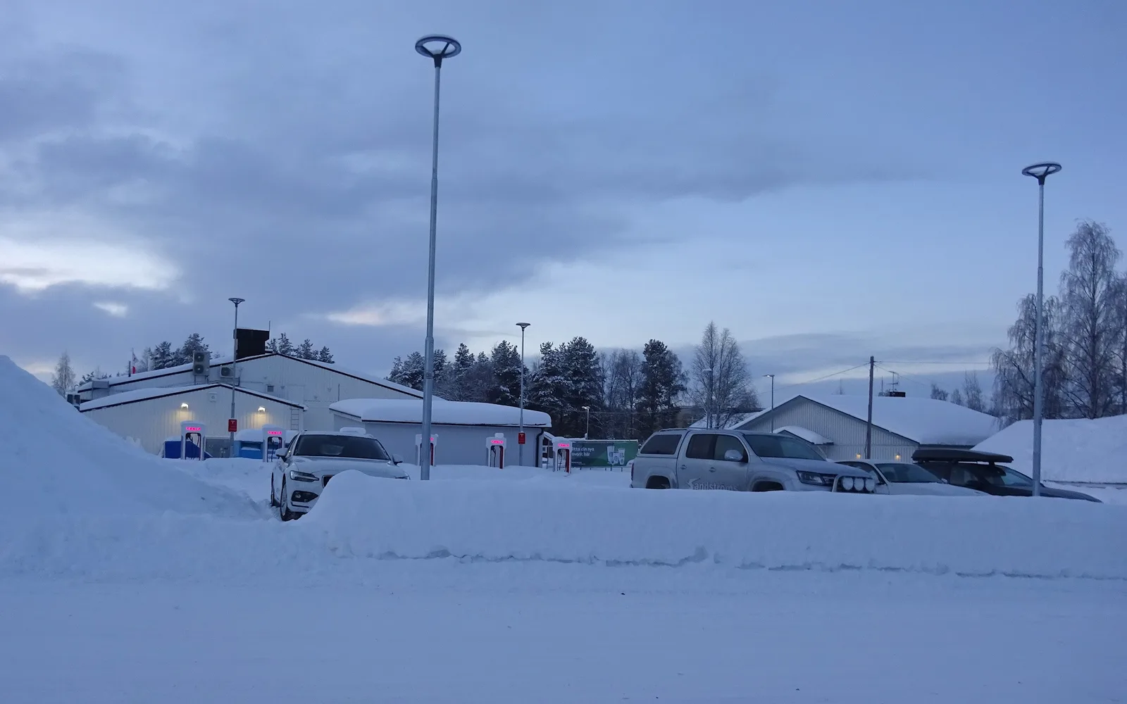 Supercharger-anlæg i vintermørke med sne omkring standerne