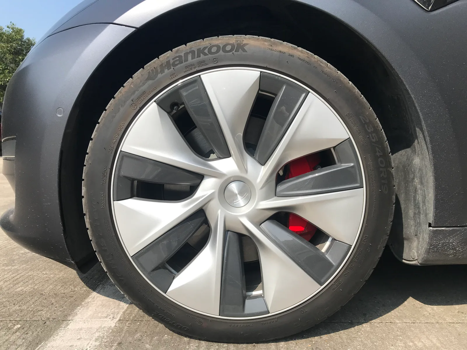 Nærbillede af et 19 tommers hjul på en grå Tesla Model 3, hvor dækkets dimension 235/40R19 kan læses på siden, og en rød bremsekaliber ses bag fælgen