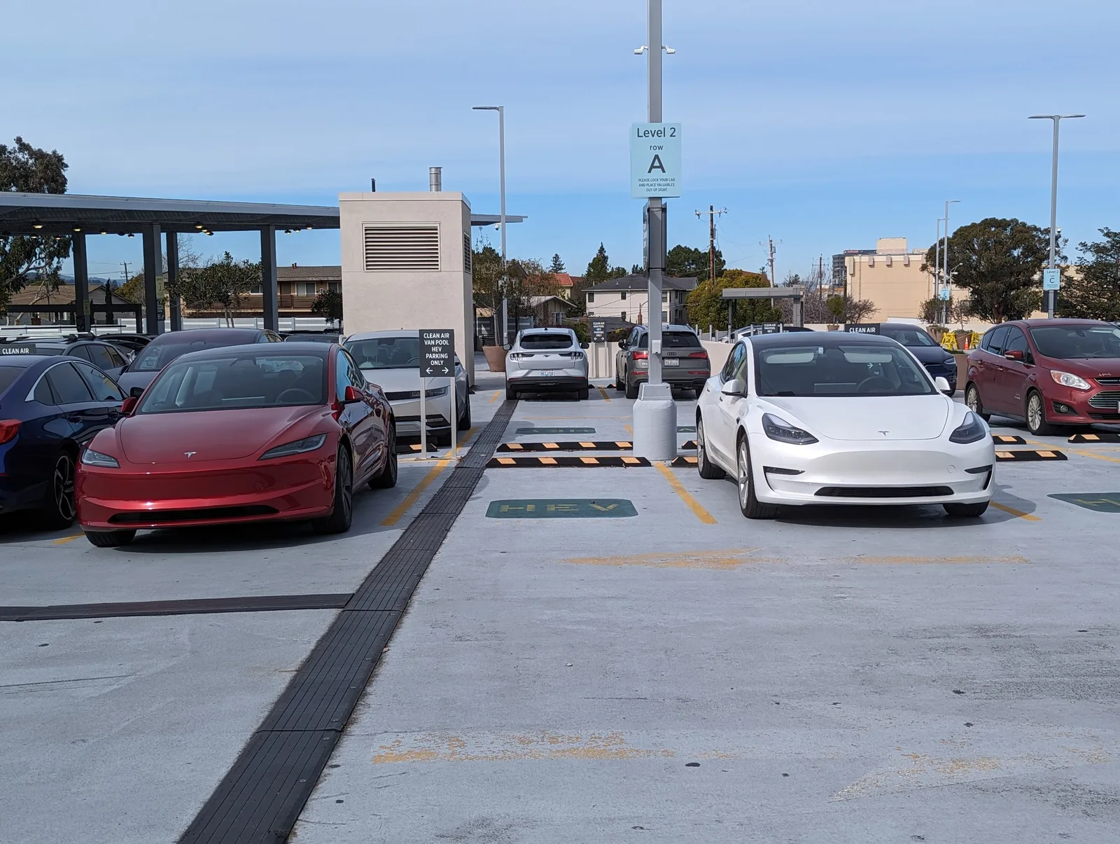 En rød Model 3 af den nye udgave og en hvid Model 3 af den gamle holder side om side i et åbent parkeringshus