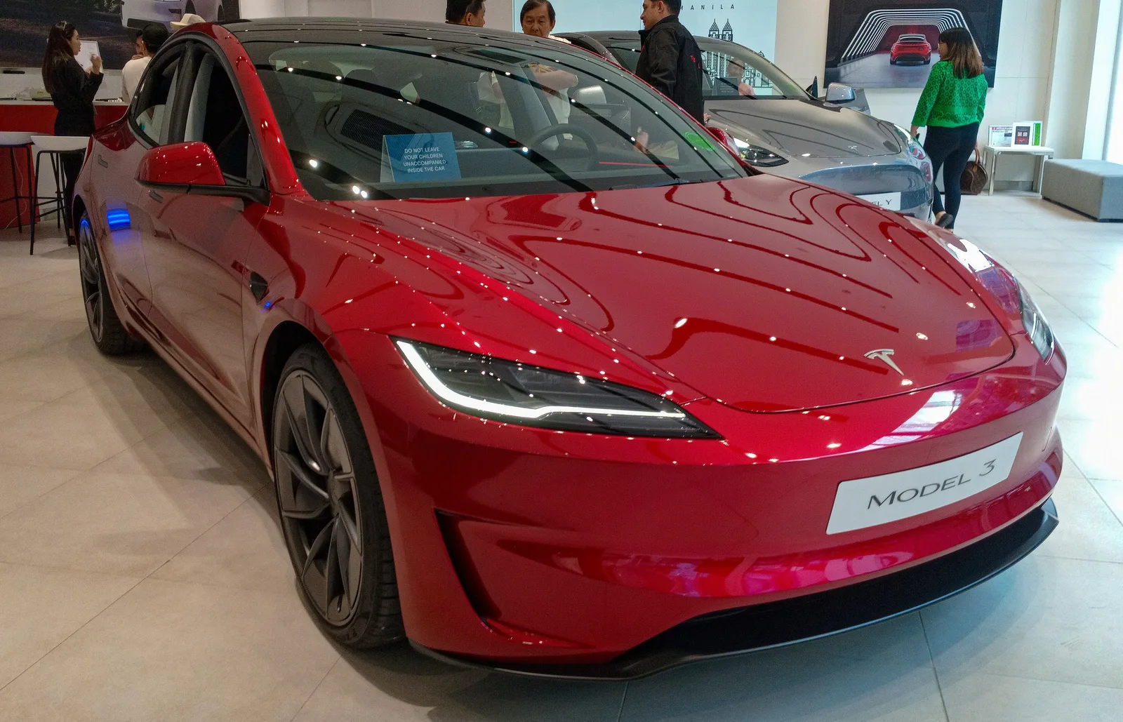 Rød Tesla Model 3 Performance set skråt forfra i en Tesla-butik