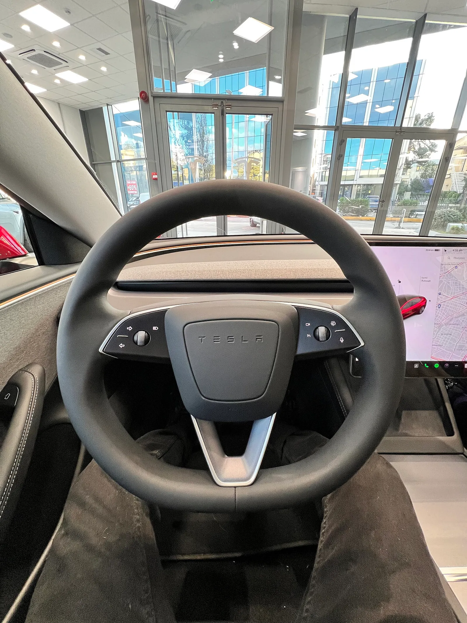 Rattet i en Model 3 uden stilke set fra førersædet, med rullehjul og knapper på begge egere og mikrofonknappen nederst til højre