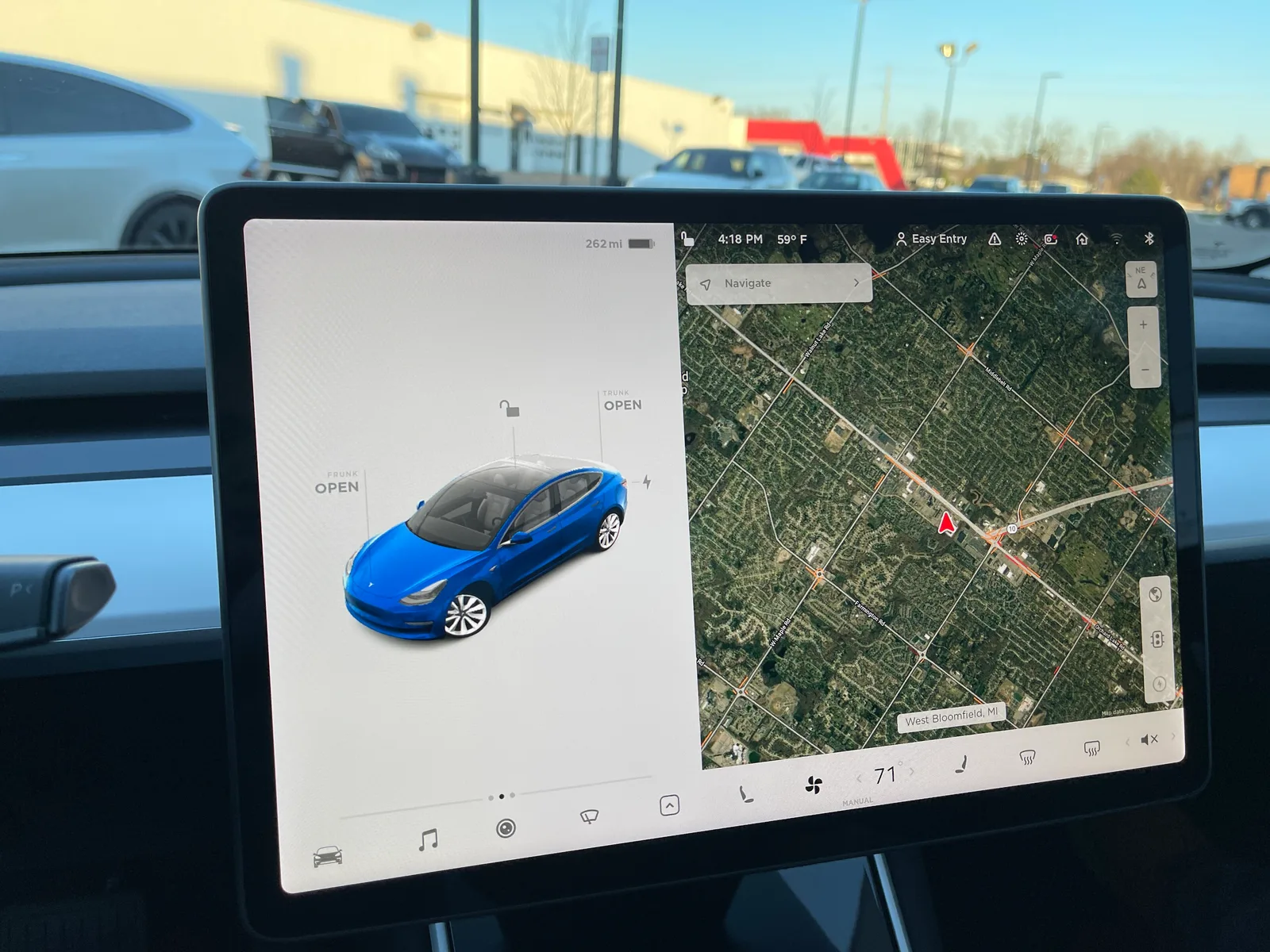 Skærmen i en Model 3 af første generation med satellitkort tændt til højre og bilen med åbne rum til venstre