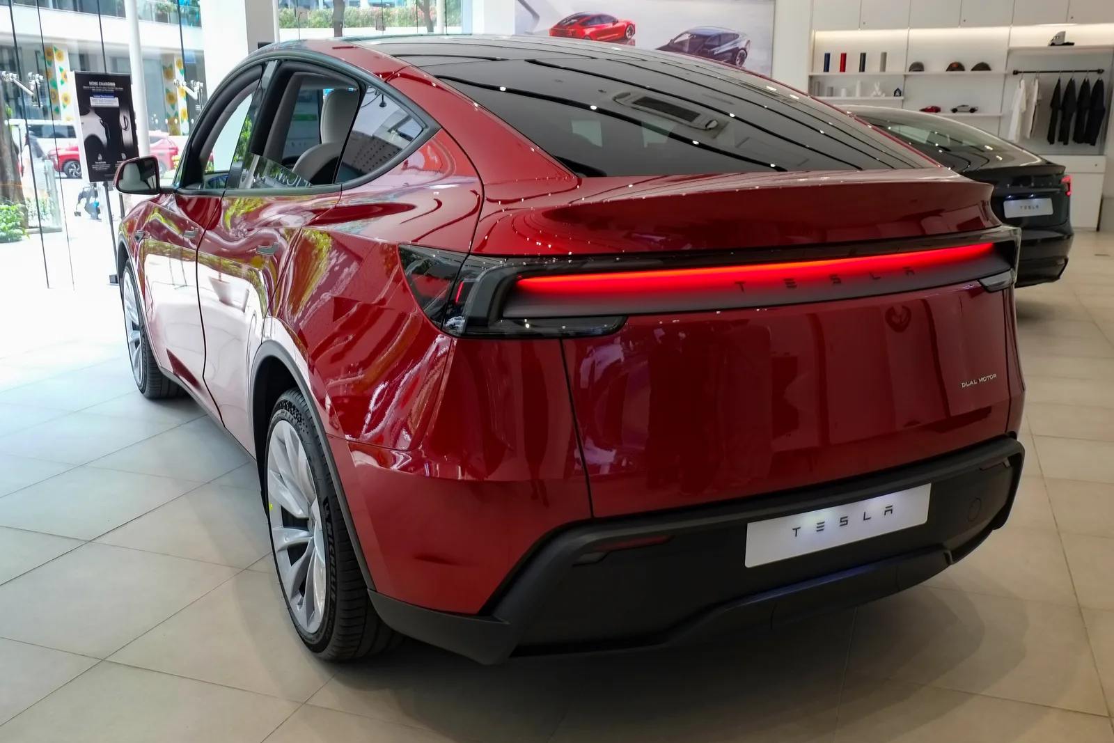 Rød Tesla Model Y af 2025-udgaven set skråt bagfra i en Tesla-butik, med den tændte røde lysstribe hen over hele bagenden