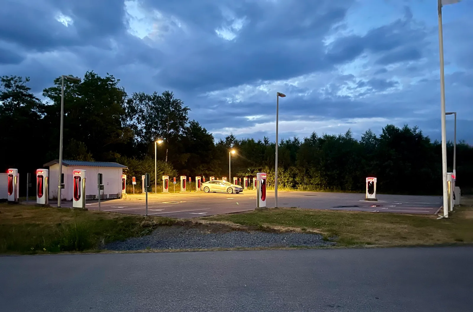 Et Supercharger-anlæg set på afstand i tusmørke, med standernes røde lys tændt